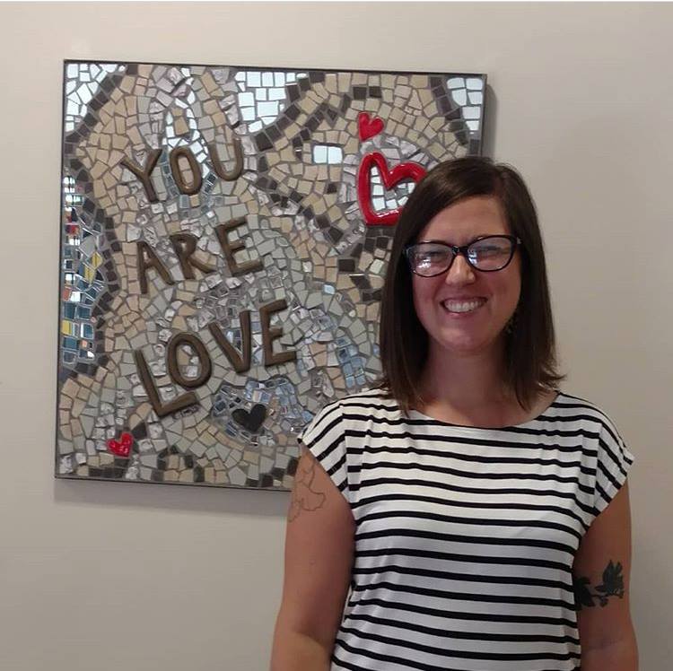 Curator Sarah McCann in front of one of her mosaics that reads 